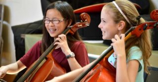 Two cello students taking music lessons